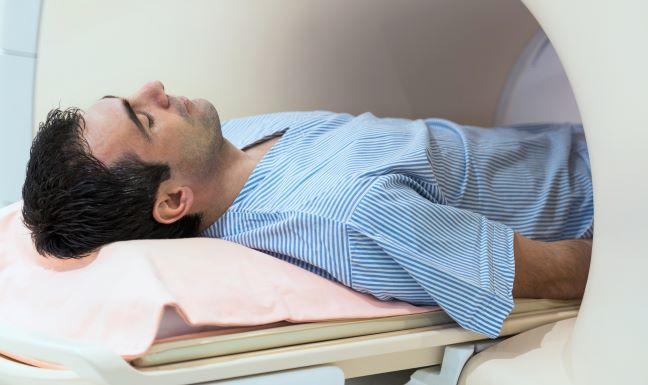 A young white male laying flat, entering an MRI machine.