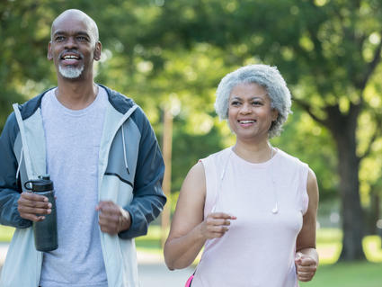 An older African American couple walking in a park.