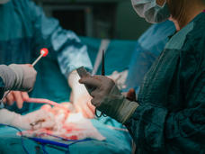 A surgical team standing over a patient in the operating room.