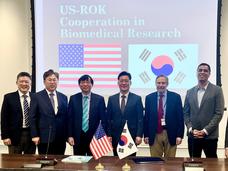 Representatives from US NCI and Republic of Korea stand in front of respective flags after signing of Memorandum of Understanding event