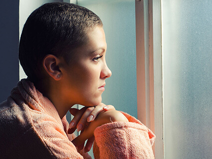 Young woman in a robe looking out a window