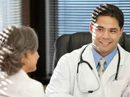 A young male doctor talking with an older female doctor.