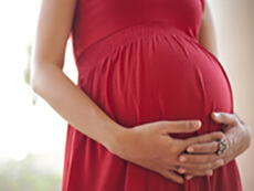 A pregnant wowman standing holding her stomach