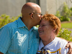 Una pareja de adultos se abrazan y se dan un beso.