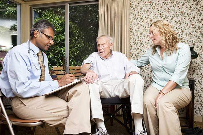 senior cancer patient talks with daughter and doctor