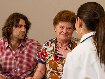 A Hispanic woman and adult son talking with a female doctor