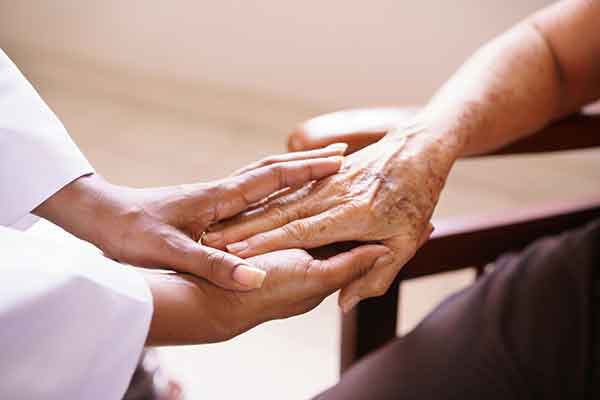 clinician’s hand holding patient’s hand