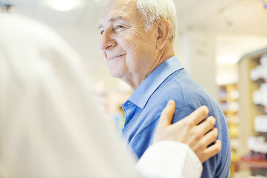 older man with doctor's hand on his shoulder