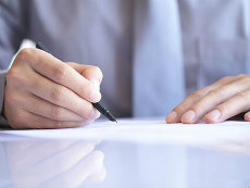 A hand holding a pen is signing a paper