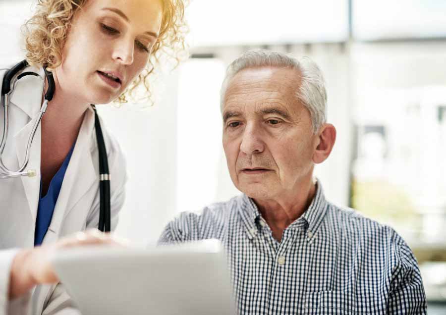 doctor discusses medical records with elderly patient