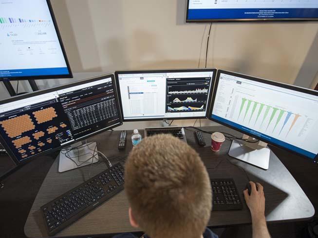 image of someone in front of three computer screens