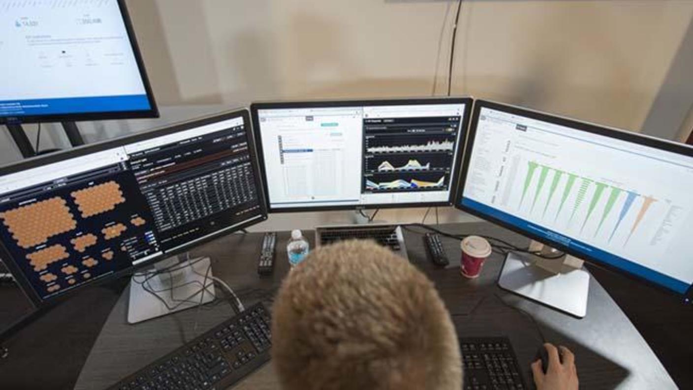 image of someone in front of three computer screens