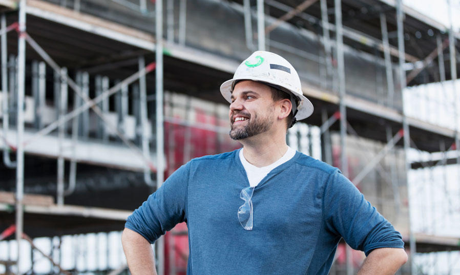 A male construction worker with a hard hat looks into the distance