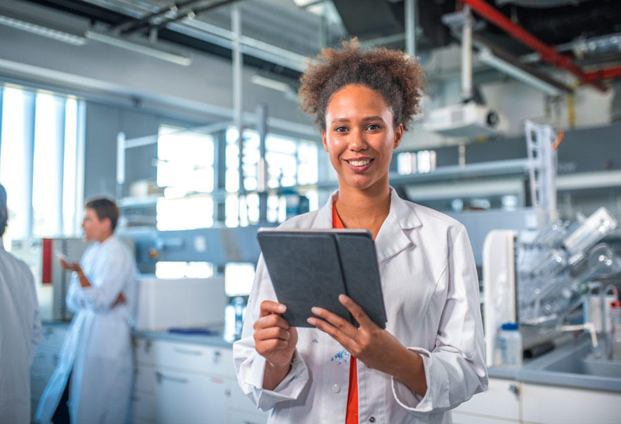 Woman wearing a lab coat looking at a tablet computer