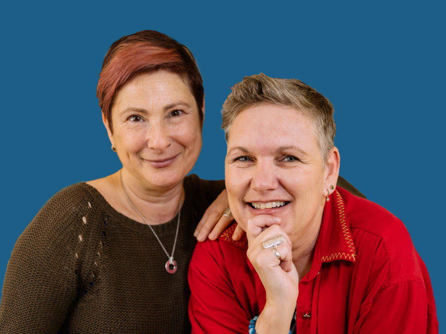 Two women smiling. One woman has her arm leaning on her partner.