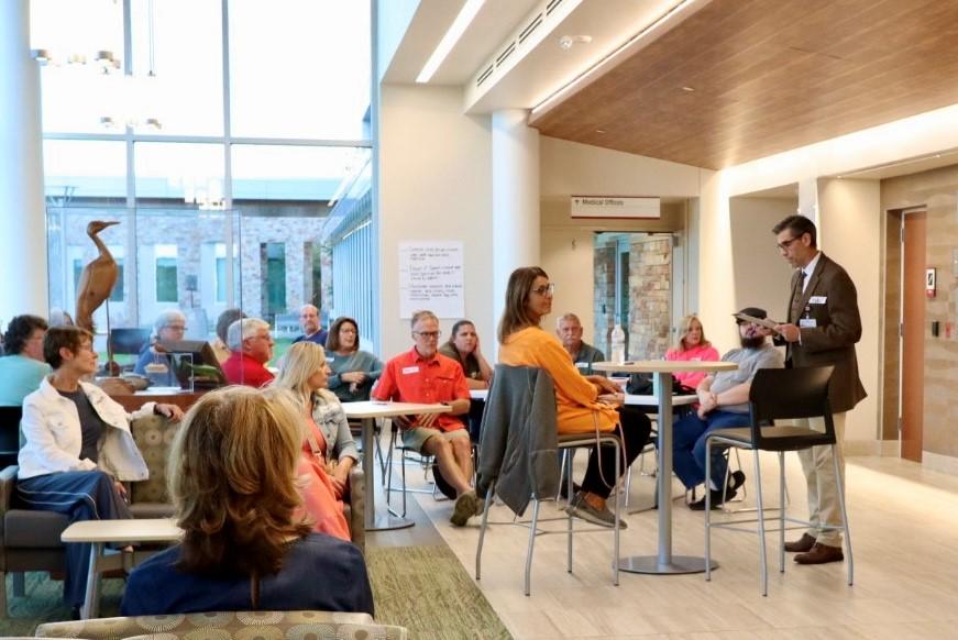 Study Principal Investigator at Marshfield Clinic, Dr. Robert Greenlee, speaking at the front of the room, introducing the research chat to event attendees, professional presentation setting, audience engagement, academic research discussion.