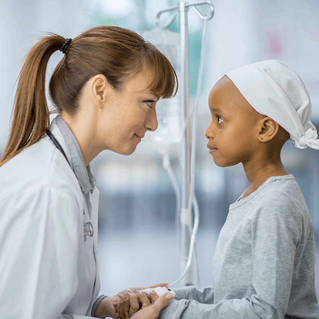 Una doctora y una paciente infantil se miran a los ojos.