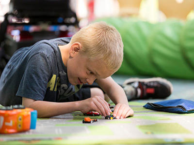 A child plays with small, toy vehicles on the floor