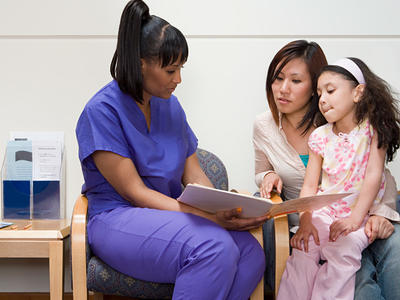 Nurse reviews a booklet with a mother and daughter