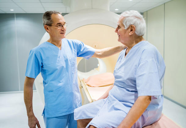 A doctor puts his hand on a patient's should before the patient goes into the MRI scanner.
