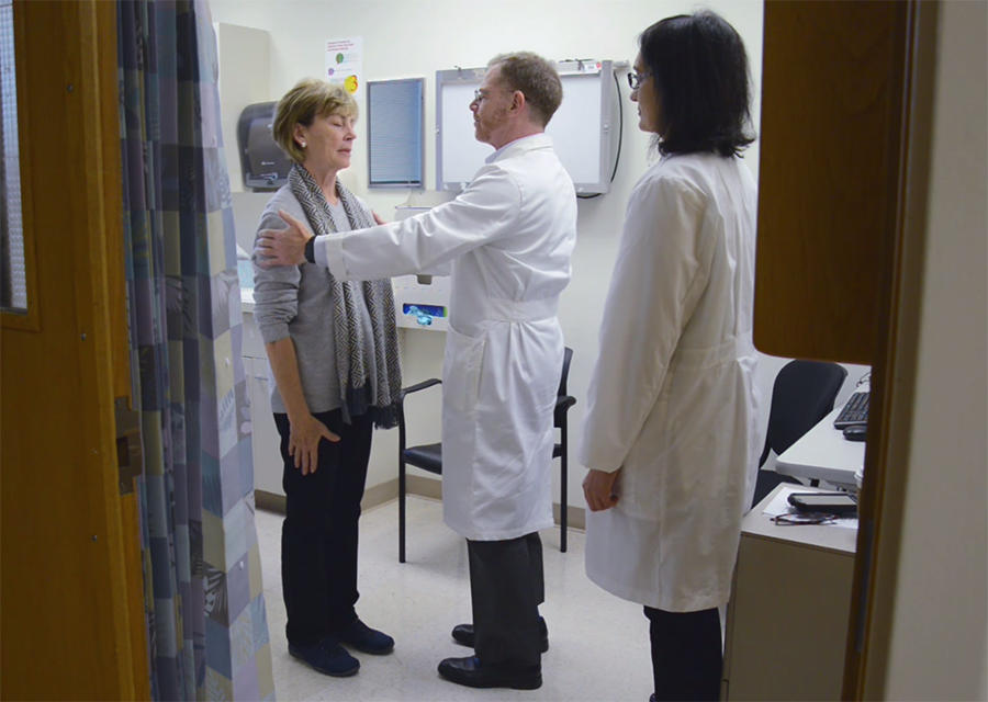 Two doctors examine a patient in a hospital room