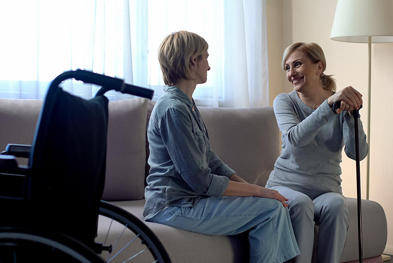 A daughter talking to her mother, who holds a cane