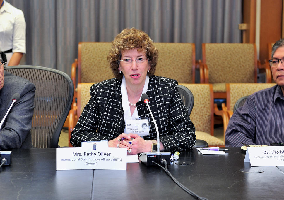 Patient advocate Kathy Oliver sitting at a table speaking into a microphone