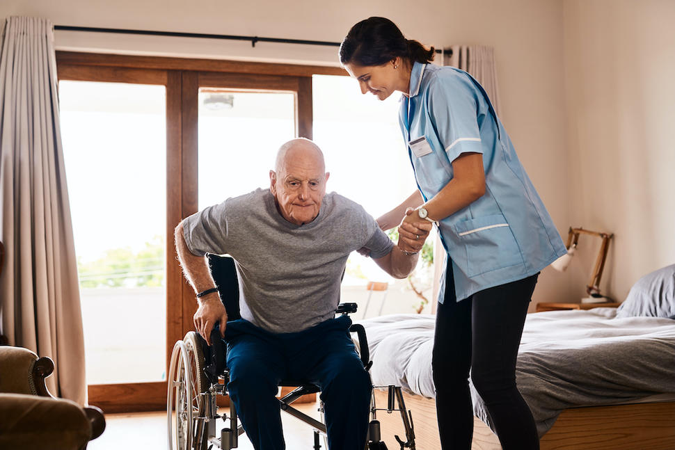 A man in a wheelchair is getting assistance from a nurse