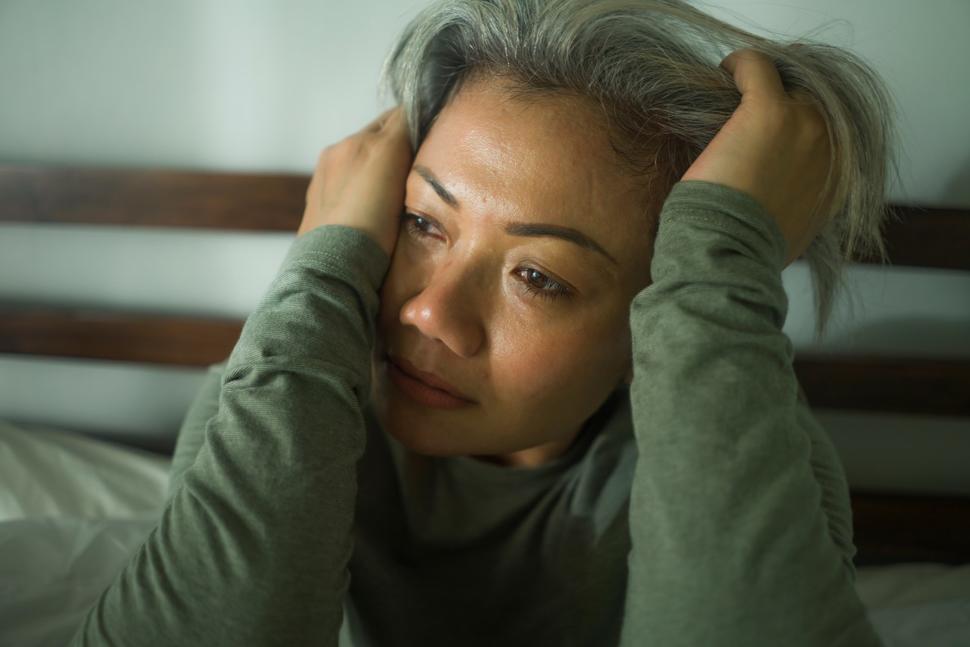 Woman holding her head in pain while crying