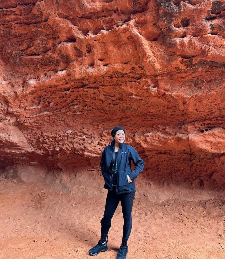 Dalouny standing outside a natural rock formation