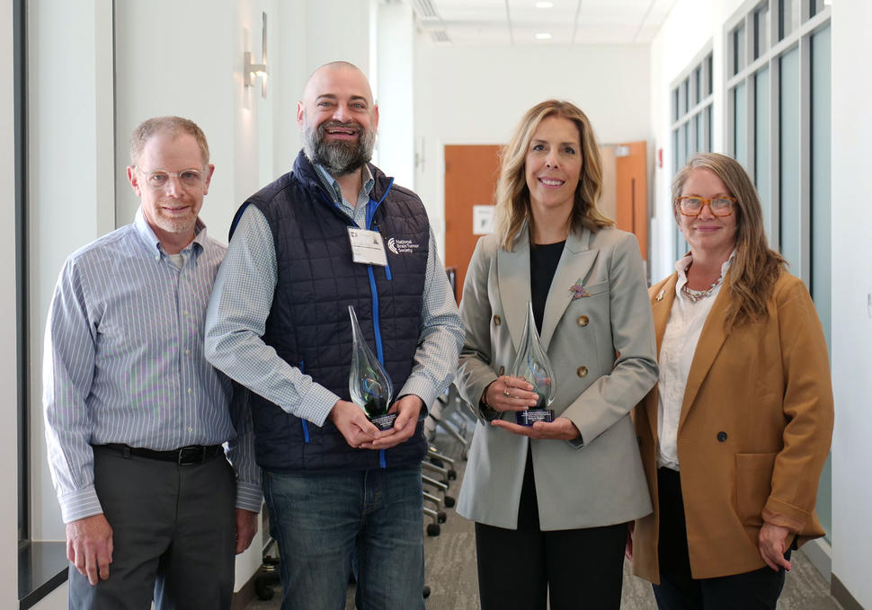 Group photo of Adam Hayen and Kim Wallgren holding awards next to Dr. Mark Gilbert and Dr. Terri Armstrong