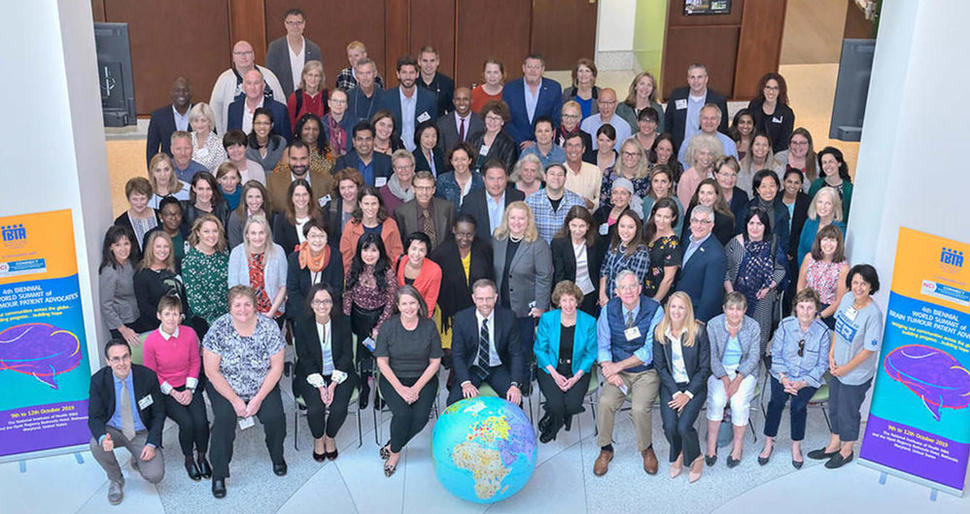 Group photo of many people standing by a large globe