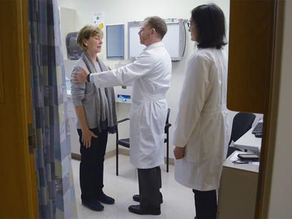Two doctors examine a patient in a hospital room