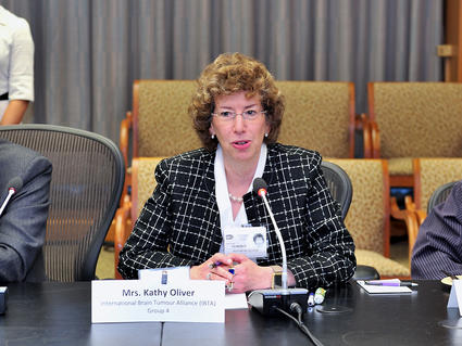 Patient advocate Kathy Oliver sitting at a table speaking into a microphone