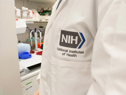 Close up of the front of a lab coat with the NIH logo