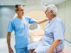 A doctor puts his hand on a patient's should before the patient goes into the MRI scanner.