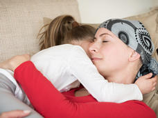 Mother with a headscarf holding her daughter on a couch