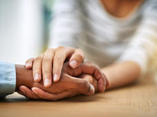 Close-up of two people holding hands across a table