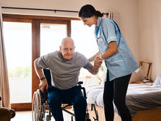 A man in a wheelchair is getting assistance from a nurse