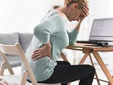 Person holding back and head in pain