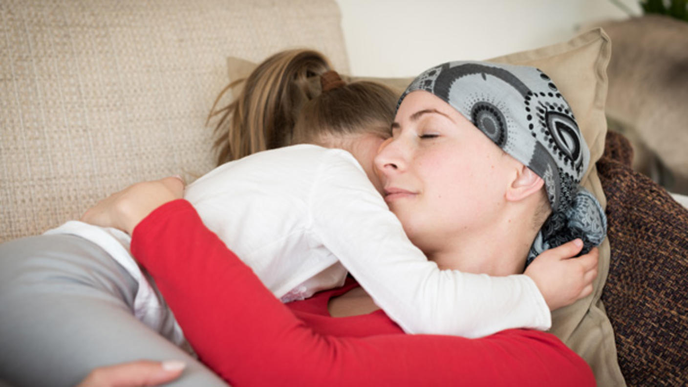 Mother with a headscarf holding her daughter on a couch
