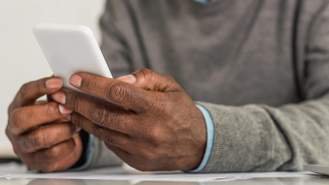 Senior man using smartphone while sitting at a table.