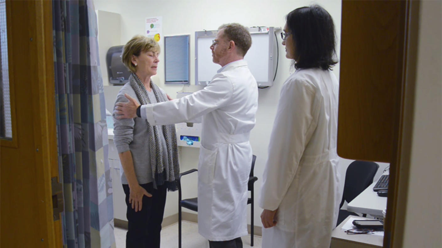 Two doctors examine a patient in a hospital room