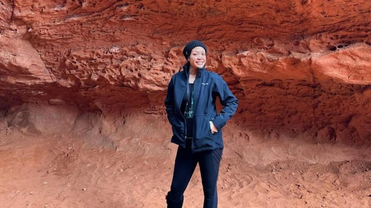 Dalouny standing outside a natural rock formation