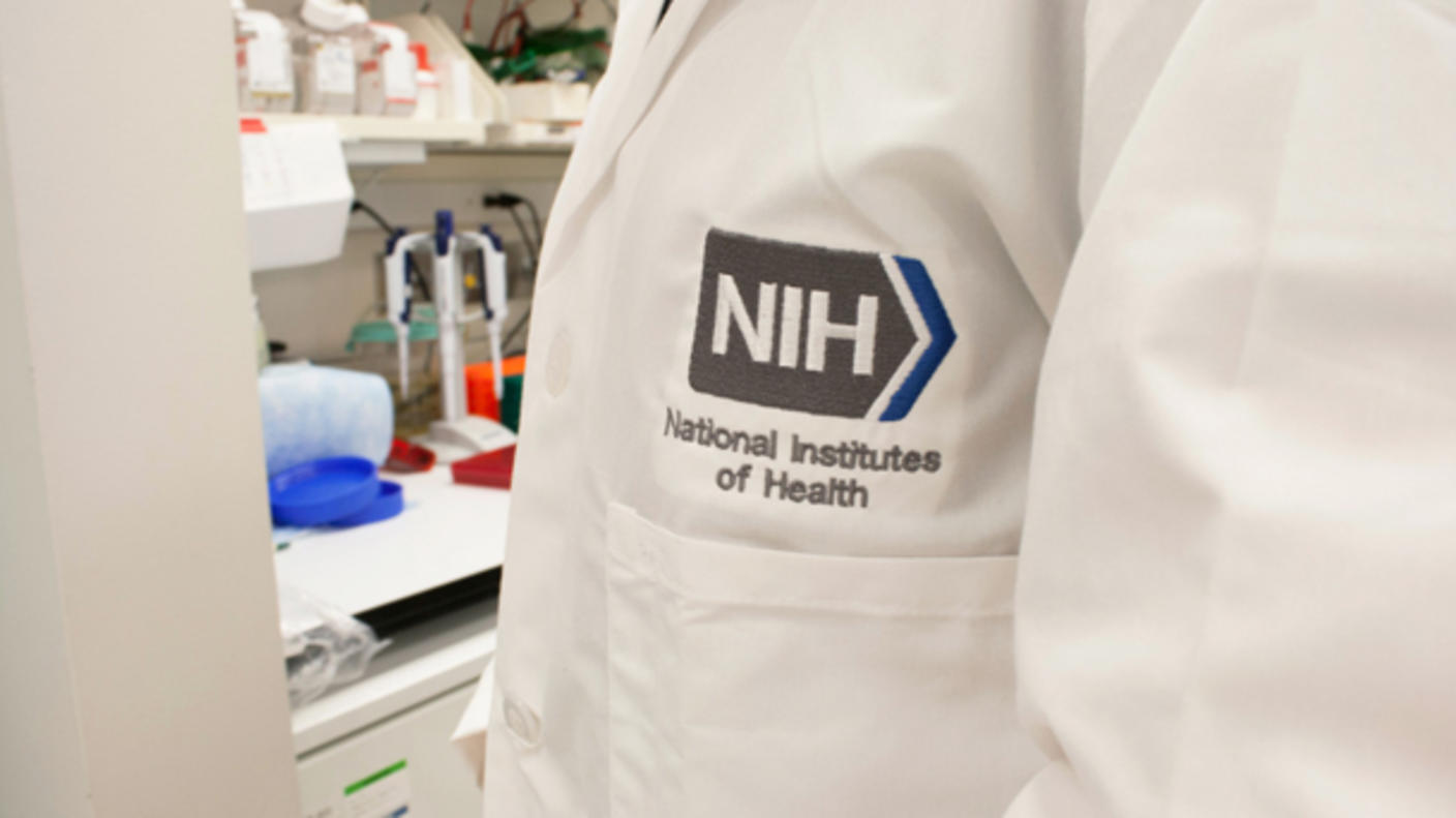 Close up of the front of a lab coat with the NIH logo