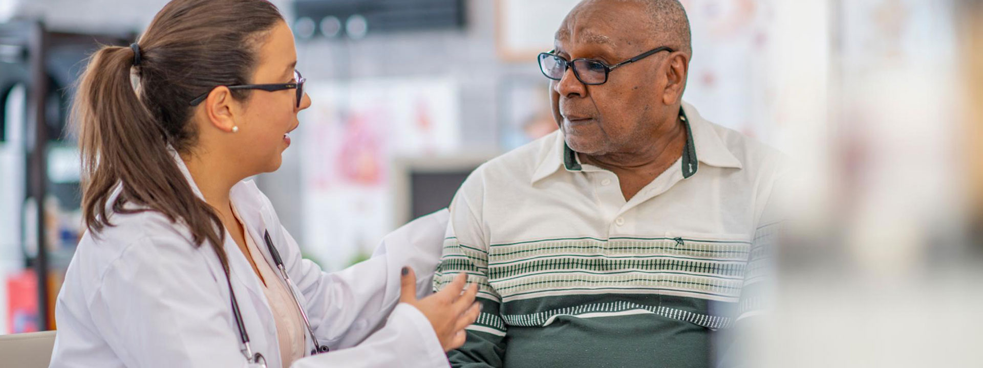 Female medical professional and older black man conversing.