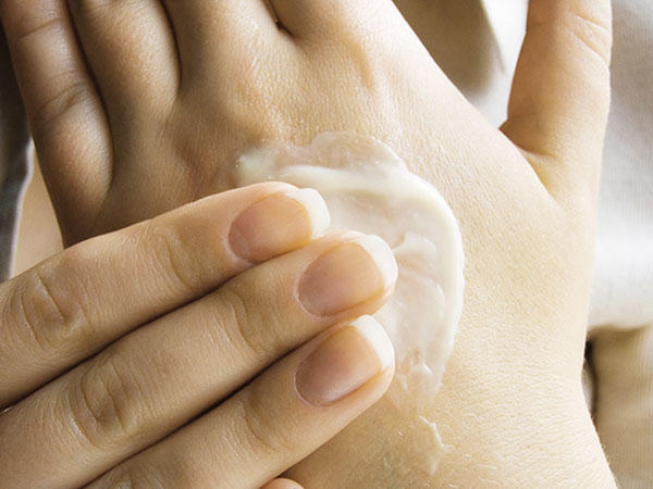 Person with cancer applying lotion to prevent dry and itchy skin. 