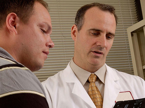 Doctor explaining information to a young male patient who is listening carefully.