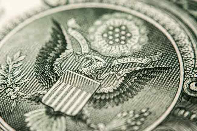 A close-up image of the seal of the United States on a US dollar bill. 