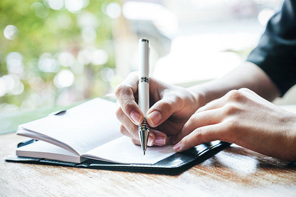 Person with cancer writing down important information in a notebook. 